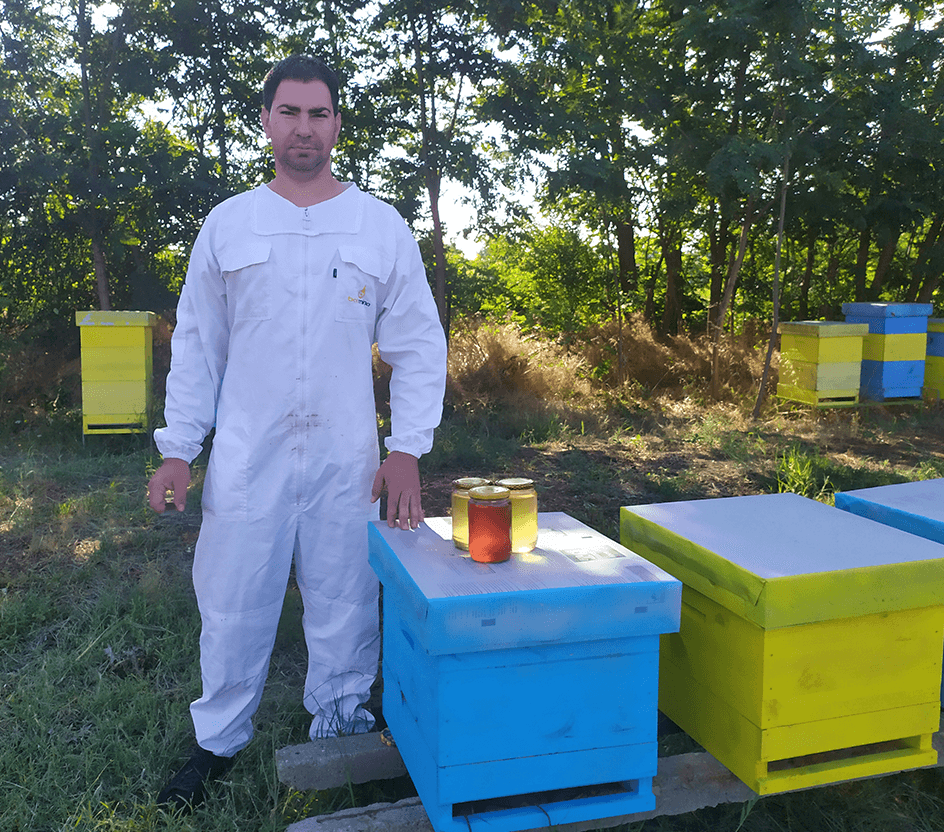 beekeeper Todor Ivanov among his hives along with three jars of honey